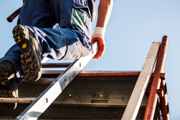 Contractor climbing a ladder to a roof