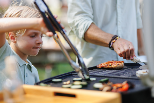 Boy and man grilling together